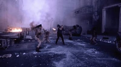a group of people running through a street next to a fire