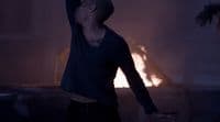 a man standing in front of a fire with his arms in the air