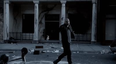 a man walking across a street in front of a building