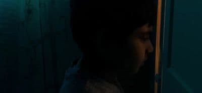 a little boy standing in front of a door