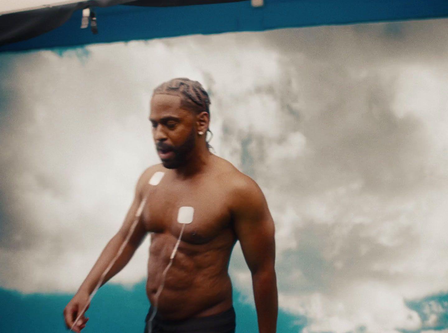 a man with no shirt is holding a frisbee