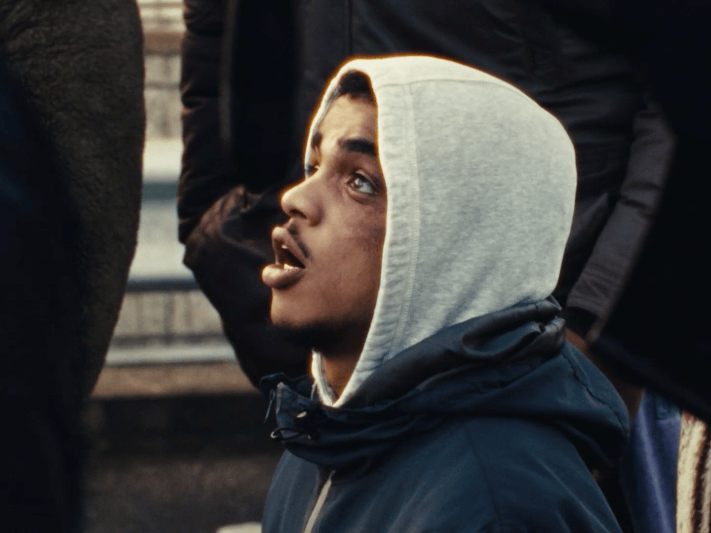a man in a hoodie standing in front of a group of people
