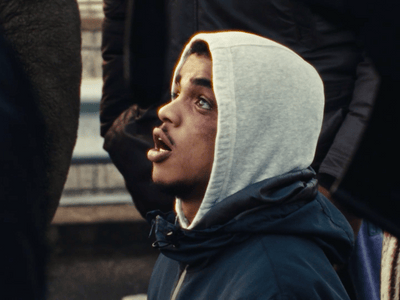 a man in a hoodie standing in front of a group of people