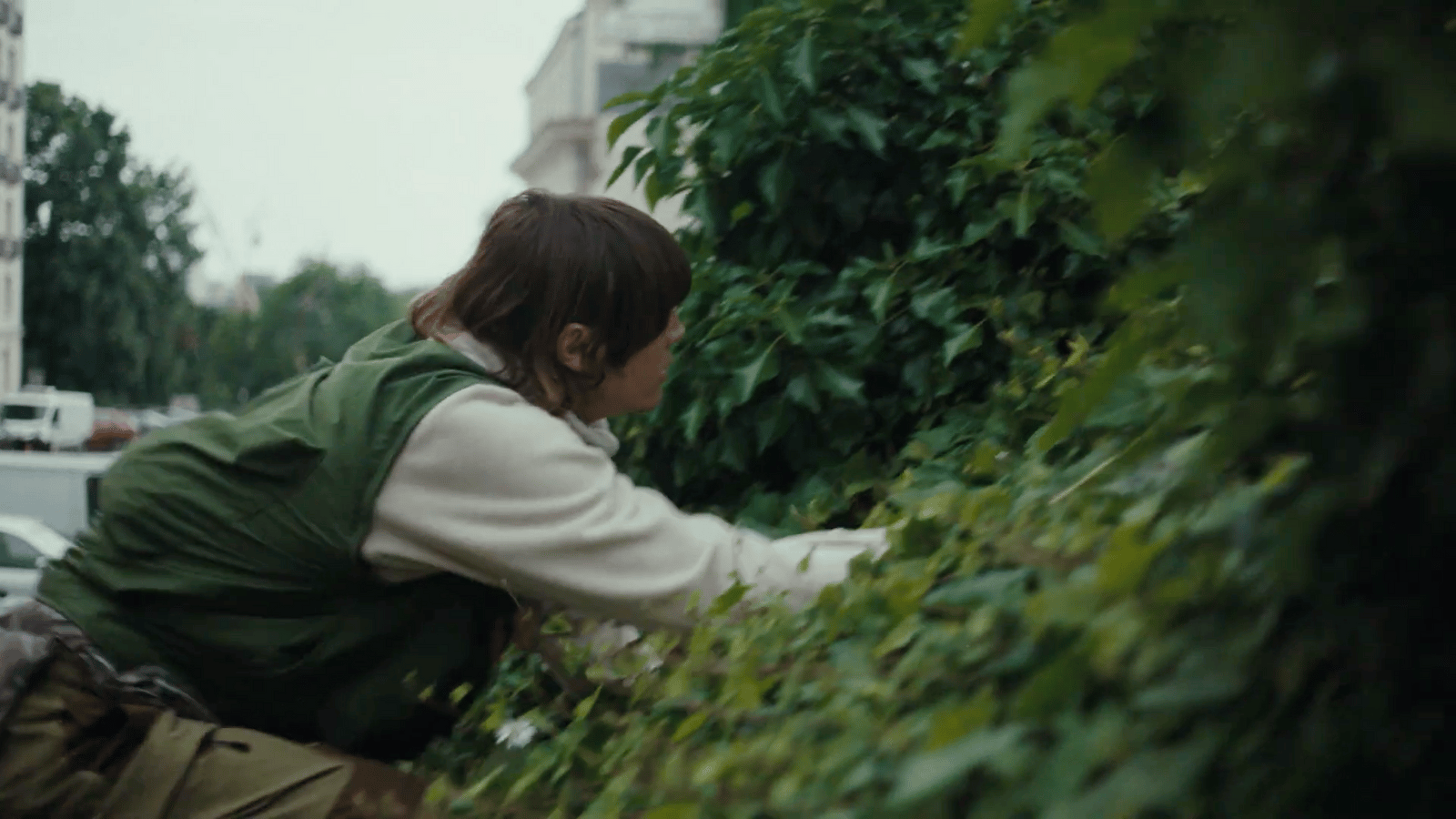 a woman is picking leaves off of a bush