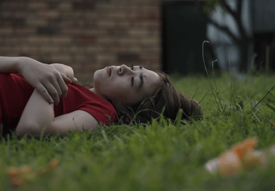 a woman laying in the grass with her eyes closed