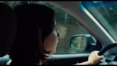 a woman driving a car with a steering wheel