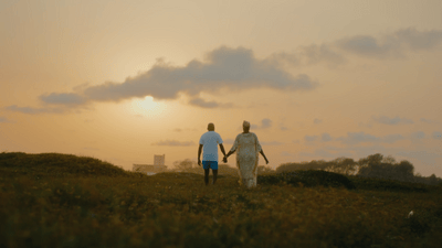 a couple of people walking across a lush green field