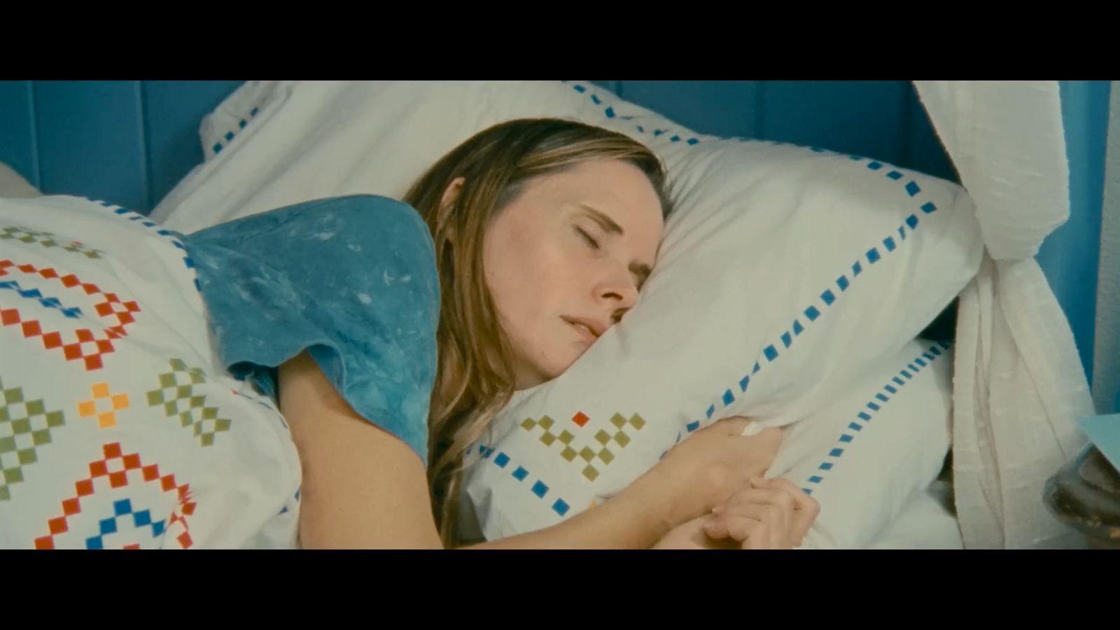 a woman sleeping in a bed with a pillow
