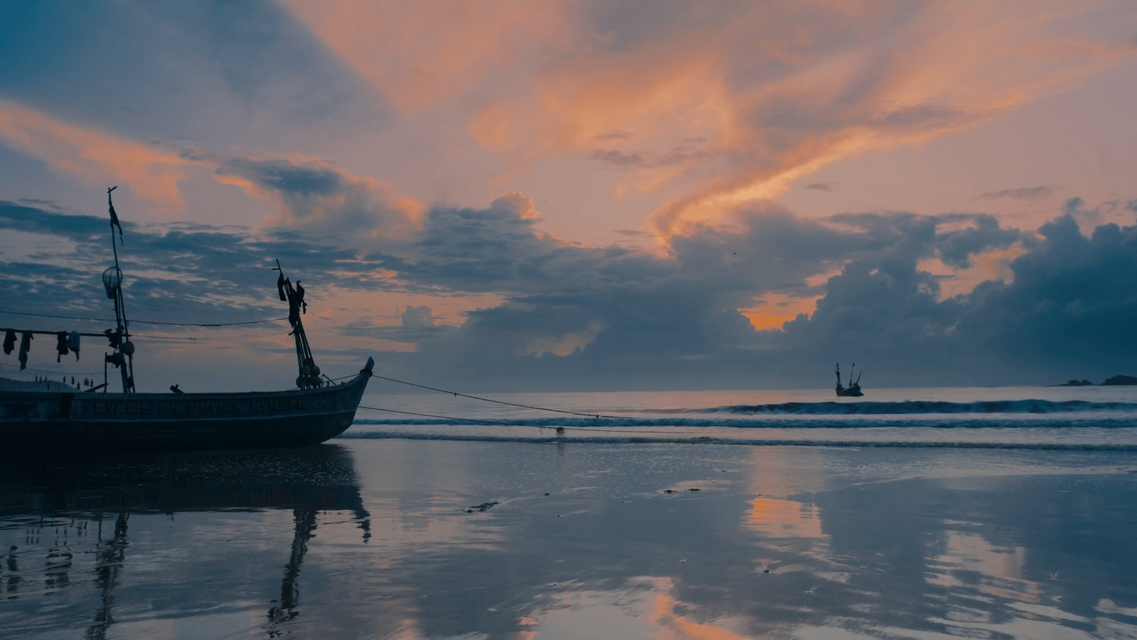 a boat sitting on top of a beach under a cloudy sky