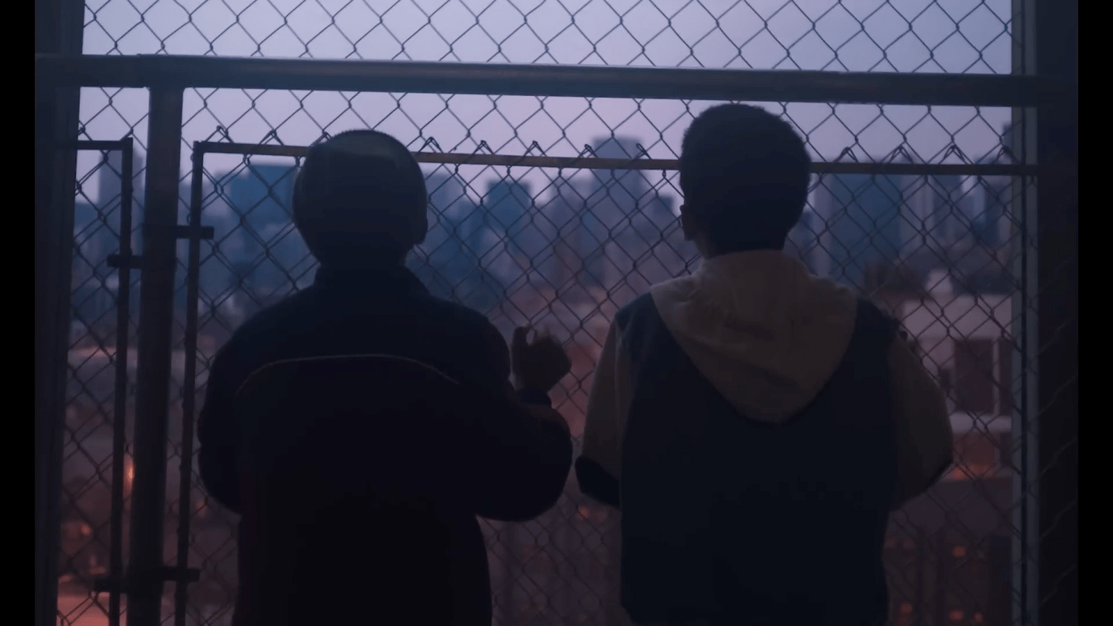 a couple of men standing next to each other near a fence