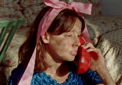 a woman with a pink ribbon on her head talking on a phone