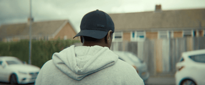 a person in a hoodie is standing in front of a house