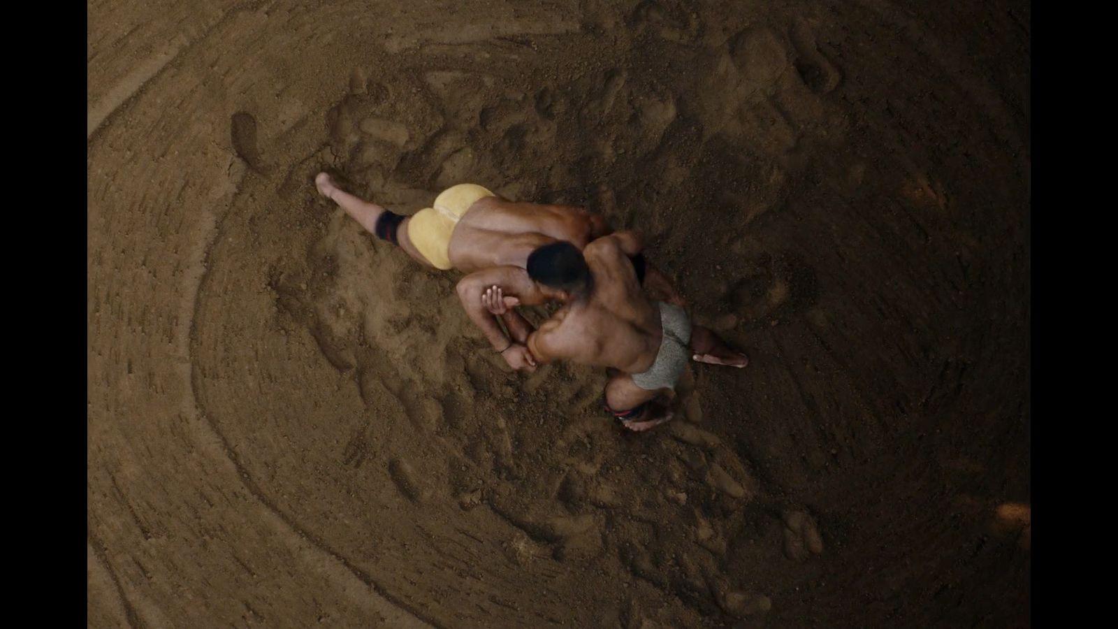 a couple of men are wrestling in the dirt
