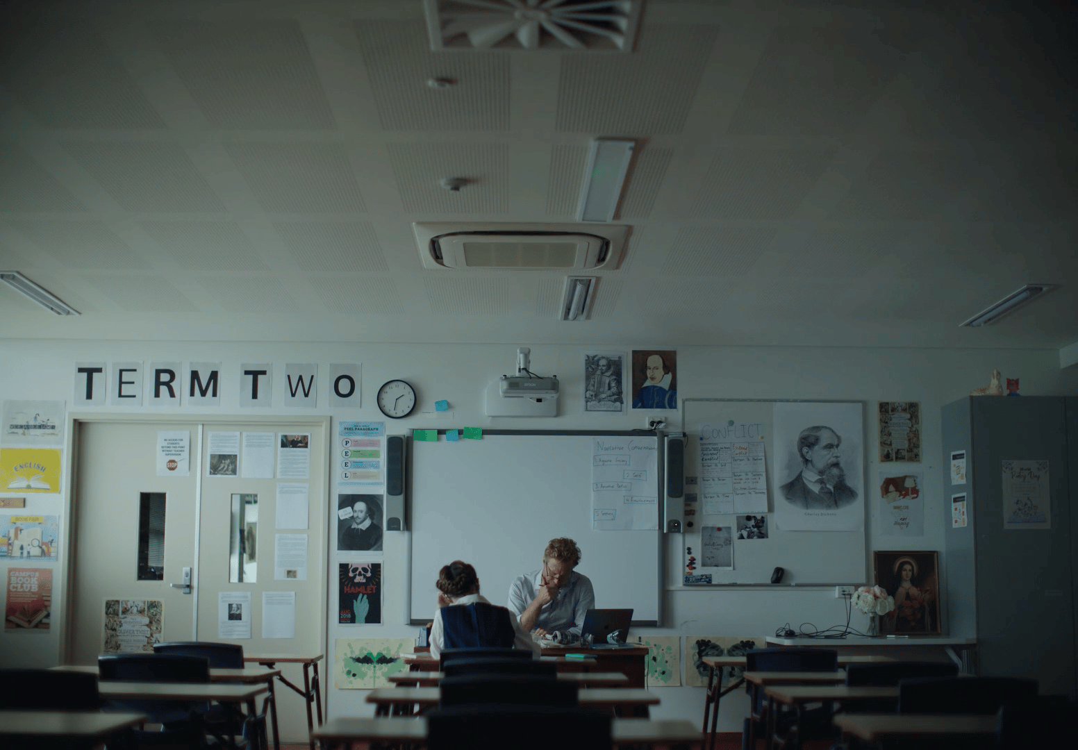 two people sitting at a table in a classroom