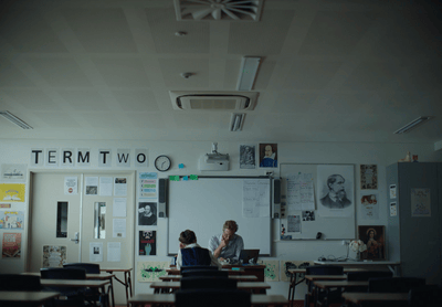 two people sitting at a table in a classroom