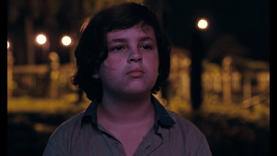 a young man stares into the distance at night