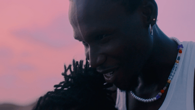 a man holding a child in front of a pink sky