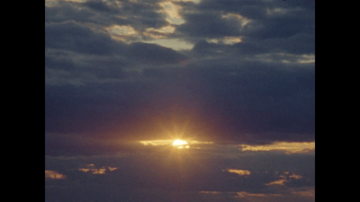 the sun is setting in the cloudy sky