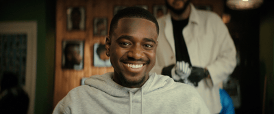 a man in a grey hoodie smiles at the camera