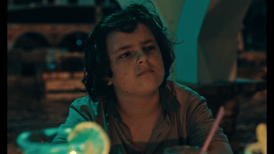 a woman sitting at a table with a drink in front of her