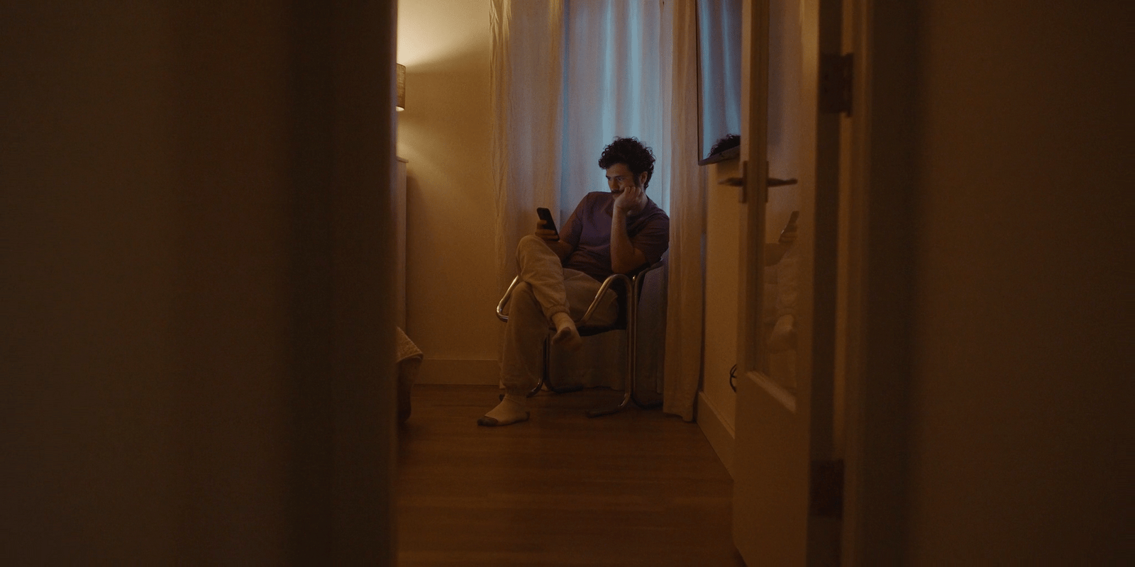 a man sitting in a chair looking at his cell phone