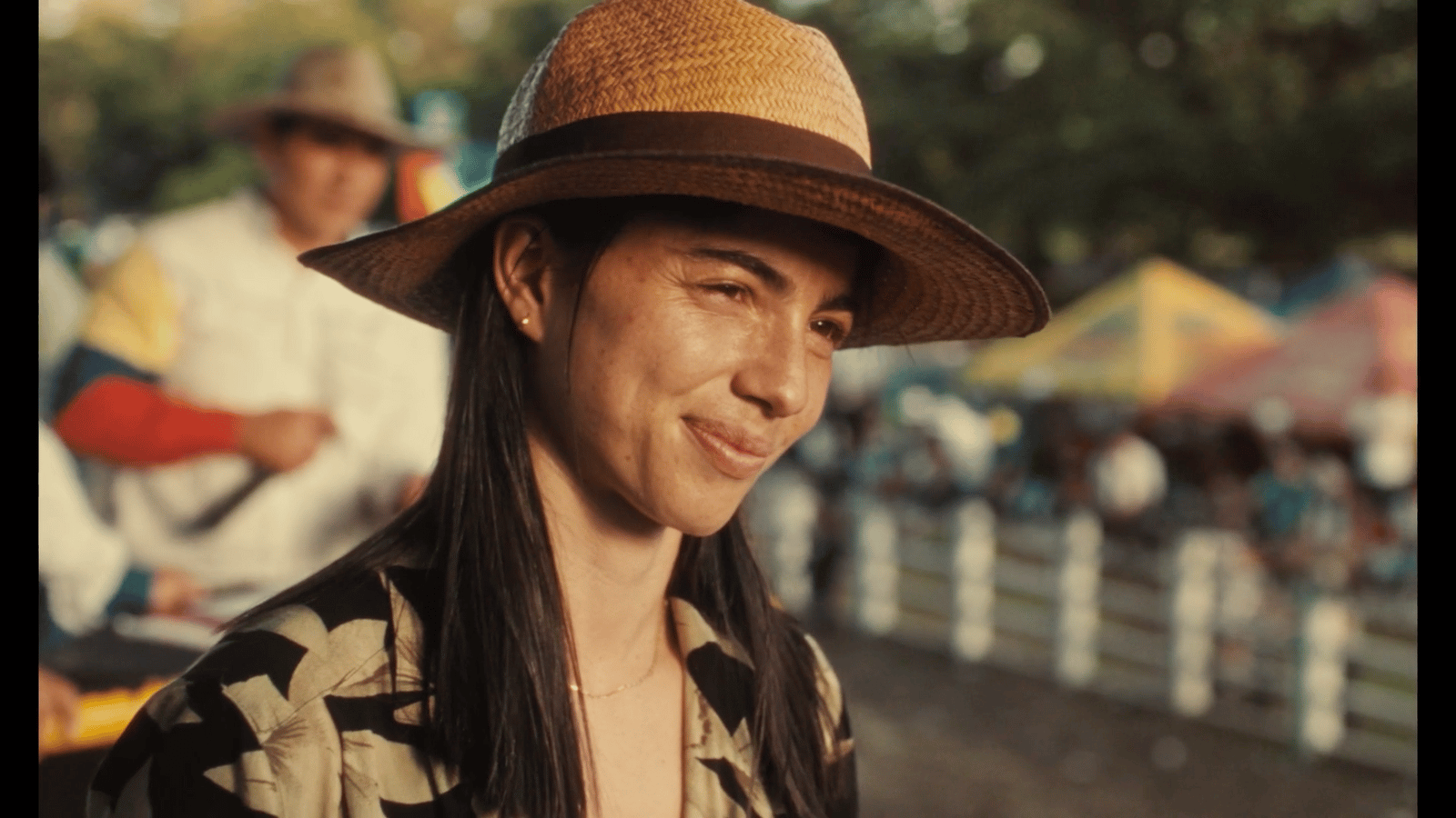 a woman wearing a brown hat standing next to a fence