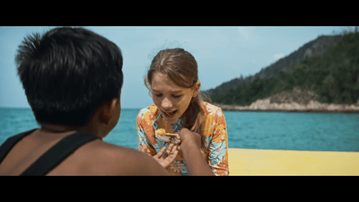 a young girl eating a piece of food next to a man