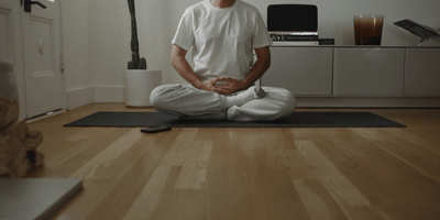 a man sitting on a yoga mat in a living room