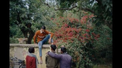 a man sitting on top of a wall next to a group of people