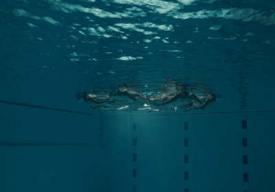 a person swimming in a pool with a surfboard