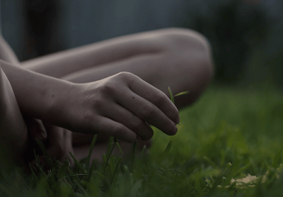 a person sitting in the grass with their hands on the ground