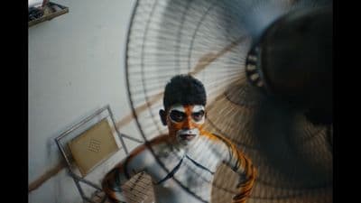 a man in a white shirt and sunglasses standing in front of a fan
