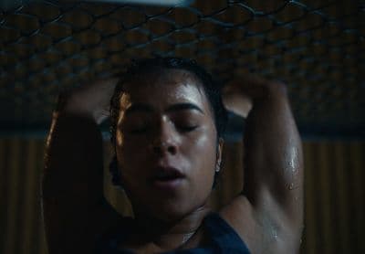 a woman in a tank top holding her head in the air