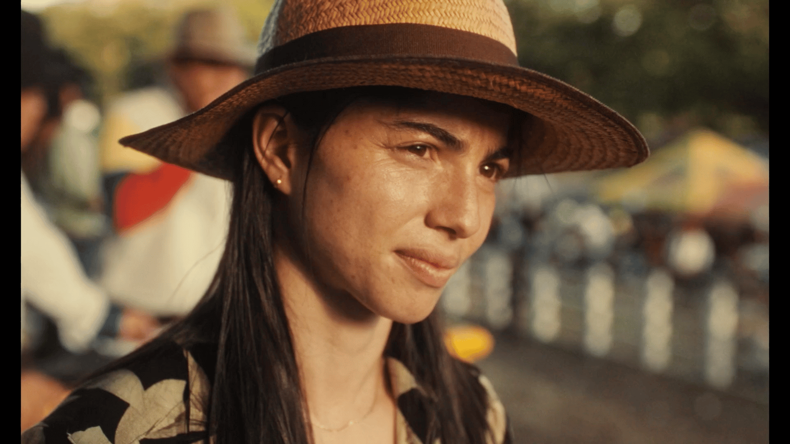 a woman wearing a hat standing next to a fence