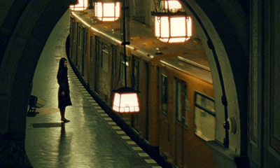 a woman standing in a train station next to a train