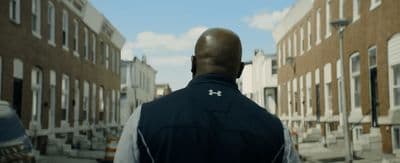 a man walking down a street next to tall buildings