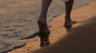 a person walking on the beach with a frisbee