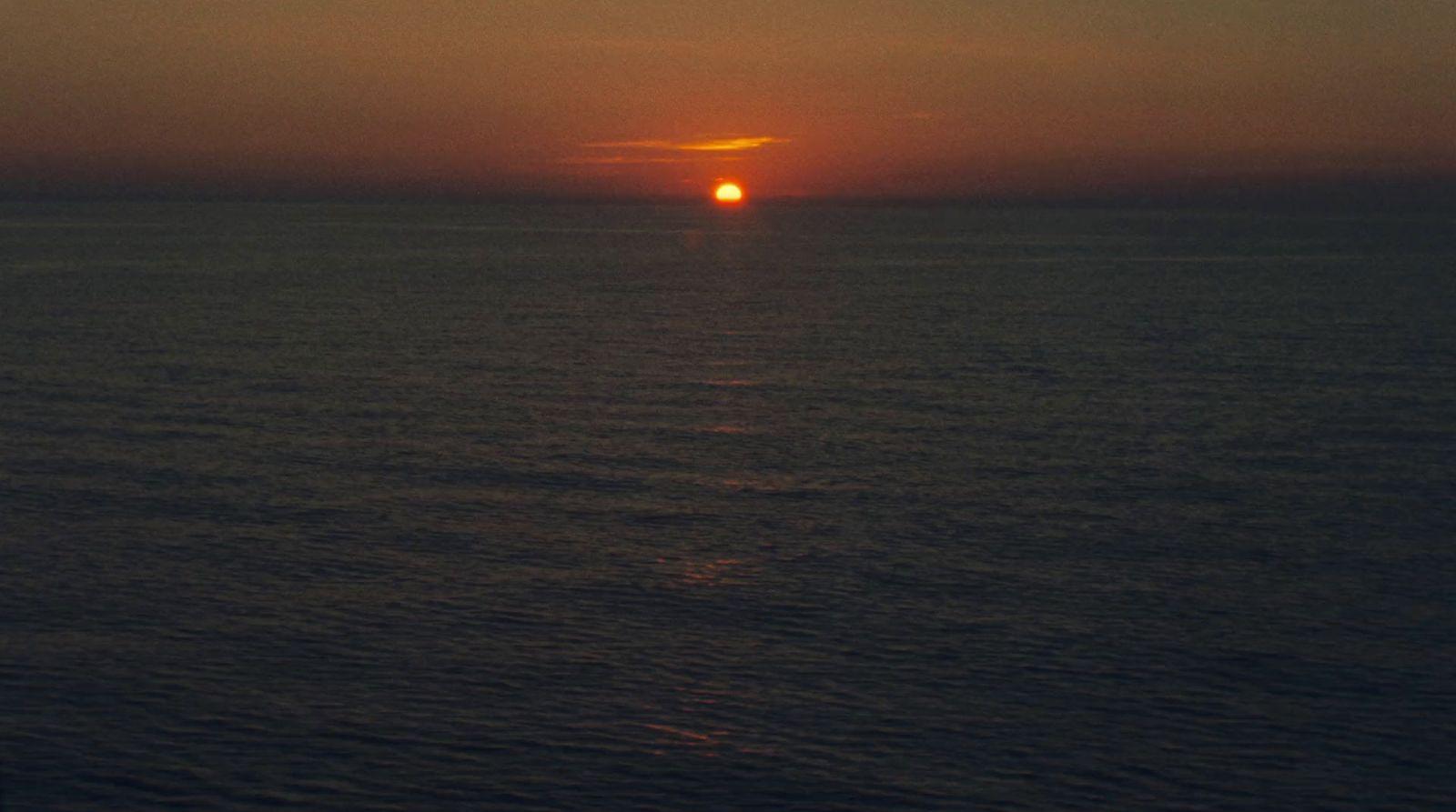 the sun is setting over the ocean on a cloudy day