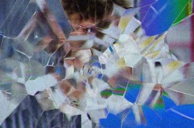 a close up of a person's face through a broken glass window