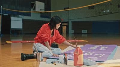 a woman sitting on the floor painting a mural