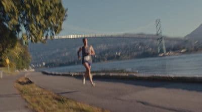 a woman running down a street next to a river