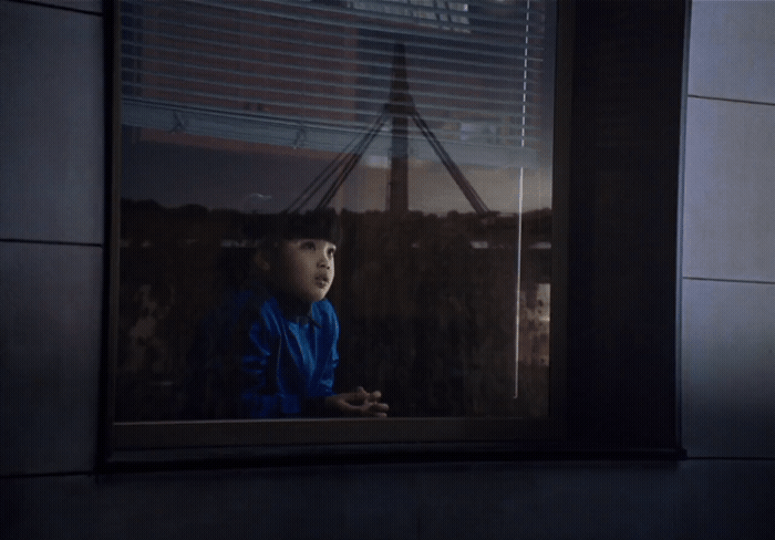 a young child looking out a window at a city