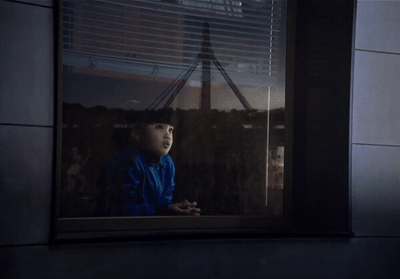 a young child looking out a window at a city