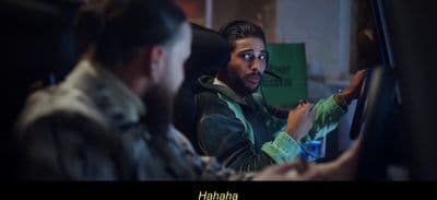 a man sitting in a car with another man behind him