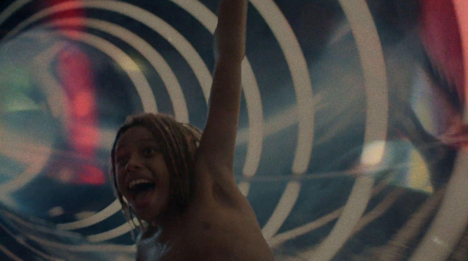 a shirtless man with his arms in the air