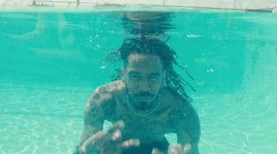 a man in a tank top swimming in a pool