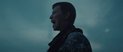 a man standing in front of a cloudy sky