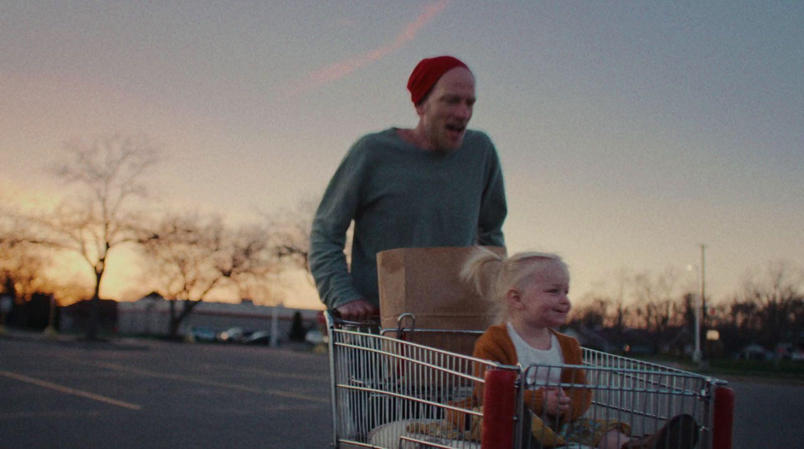 a man pushing a shopping cart with a little girl in it
