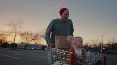 a man pushing a shopping cart with a little girl in it