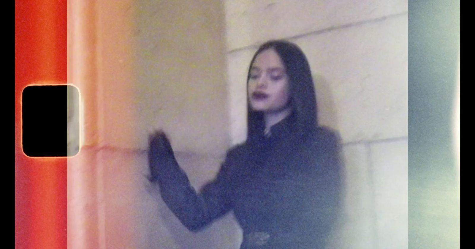a woman standing next to a wall holding a cell phone